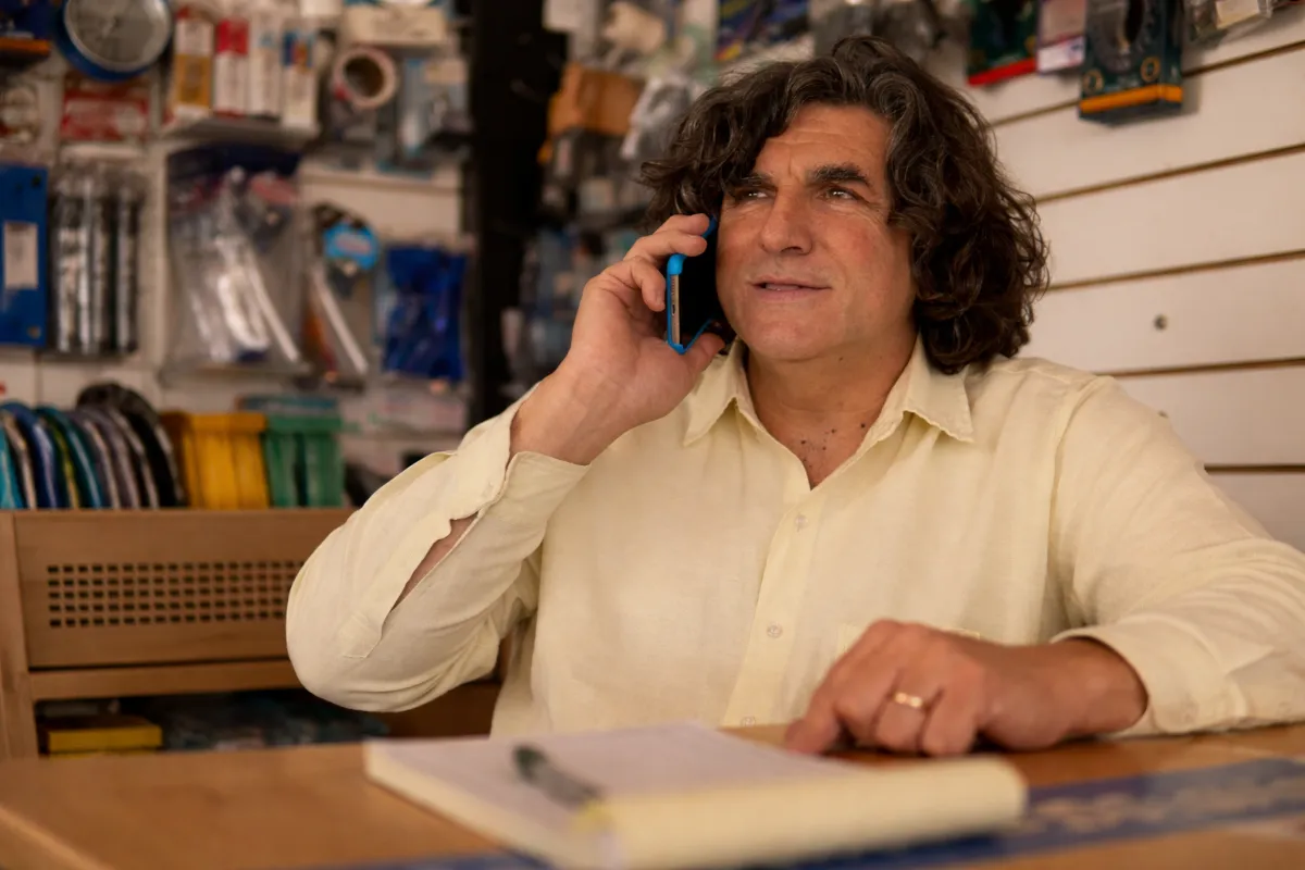 Hombre en corralón hablando por teléfono mientras toma notas en un cuaderno