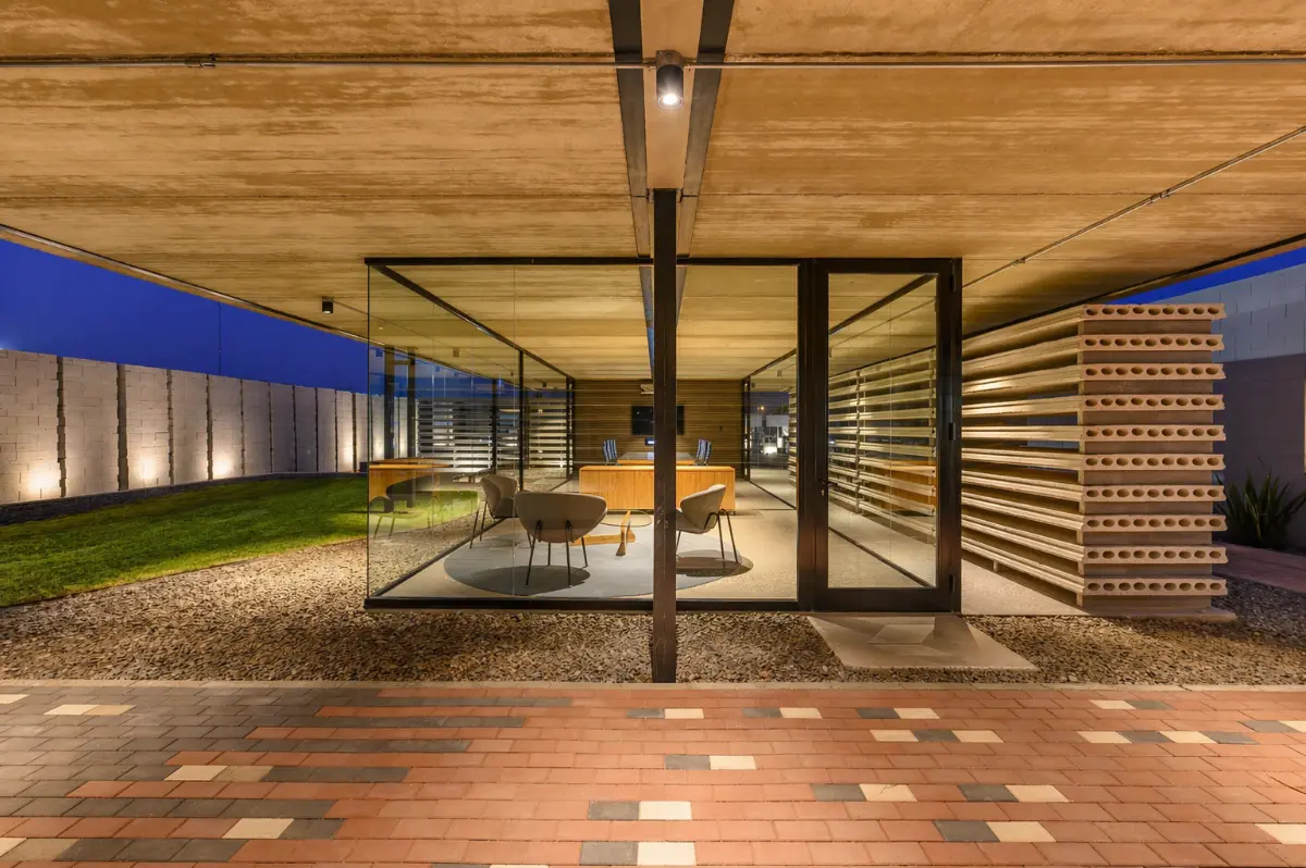 Sala comercial moderna con estructura de vidrio y bloques de hormigón, iluminada de noche con diseño arquitectónico minimalista